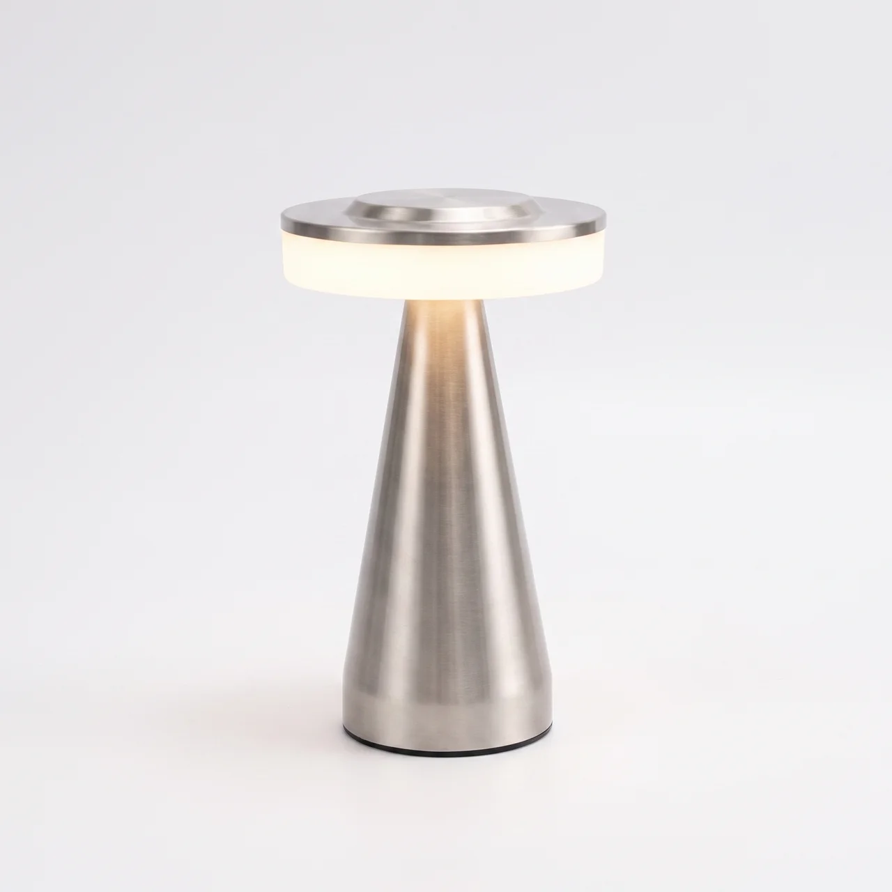 A modern table lamp with a brushed metal base and a circular lighted shade, shown on a clean white background.
