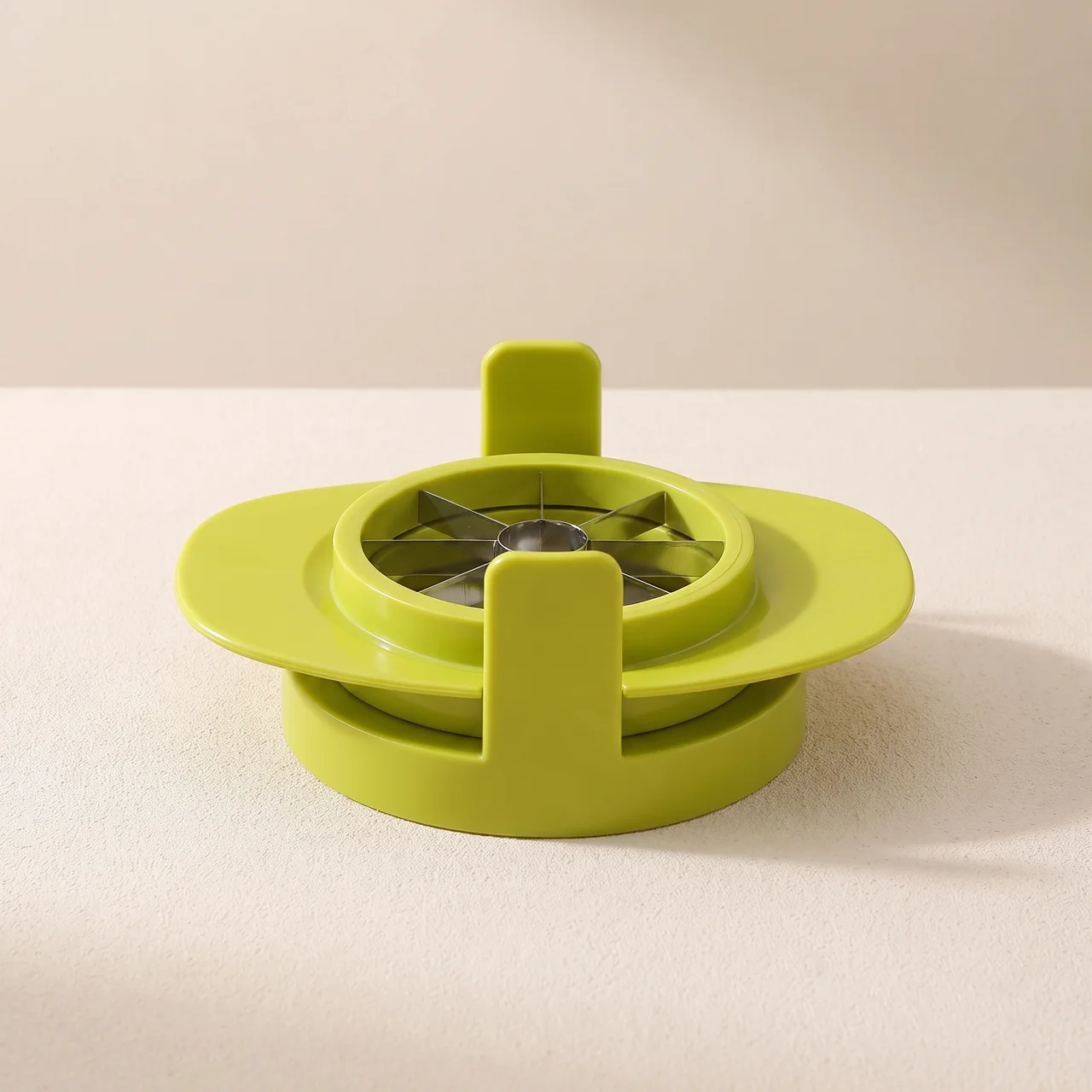 A bright lime green plastic kitchen utensil, likely a garlic press or food processor attachment, shown on a neutral beige background.
