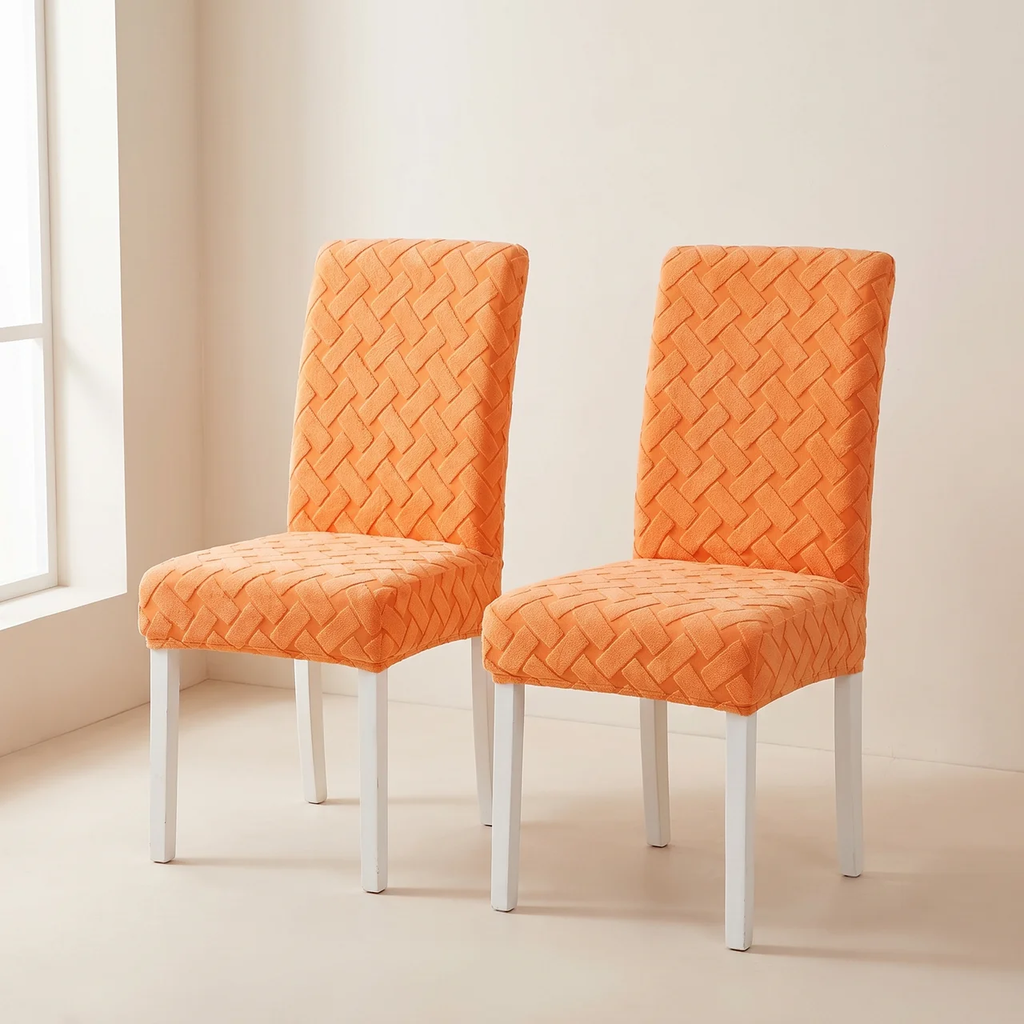 Two upholstered dining chairs with bright orange textured fabric and white legs, shown in a clean indoor room setting.