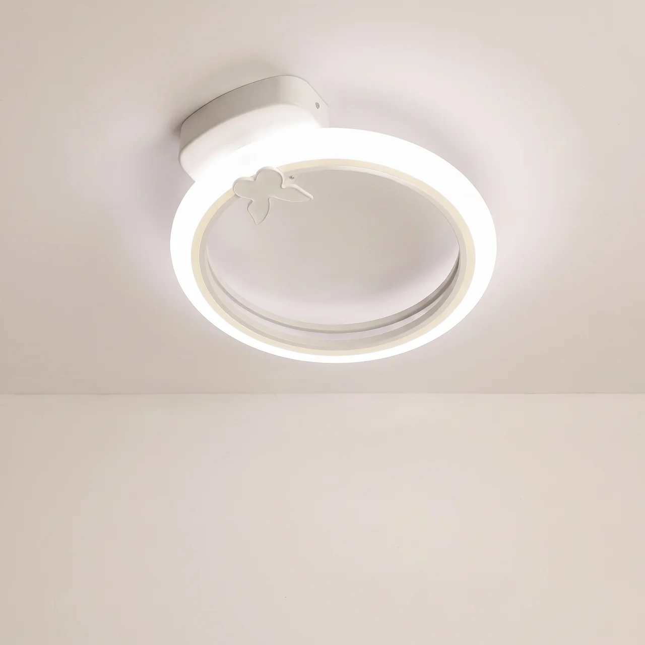 A modern circular LED ceiling light fixture with a butterfly accent, shown installed on a plain off-white ceiling.