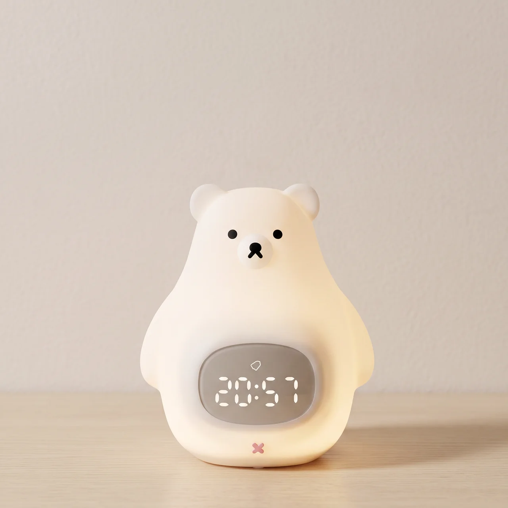A cute bear-shaped digital alarm clock with a warm white glow, featuring a digital display showing 20:57 on a light wooden surface against a neutral beige wall.