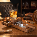 A wooden cigar and whiskey accessory set on a wooden desk, featuring a cigar tray with a cigar resting on it, a cigar cutter drawer, a glass holder with an iced whiskey, eyeglasses, and stacked books in a warm, dimly lit room.