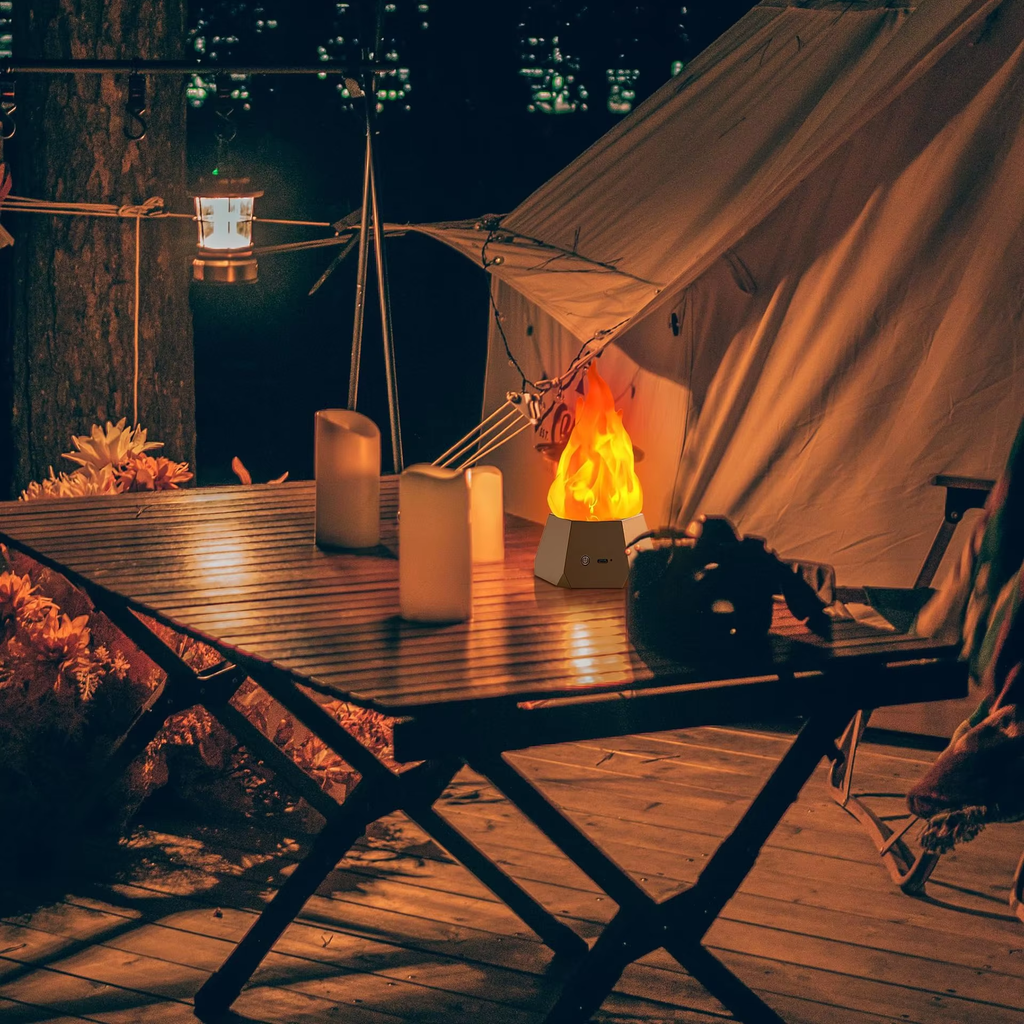 Camping scene with a tent, table, candles, and fire pit at night.