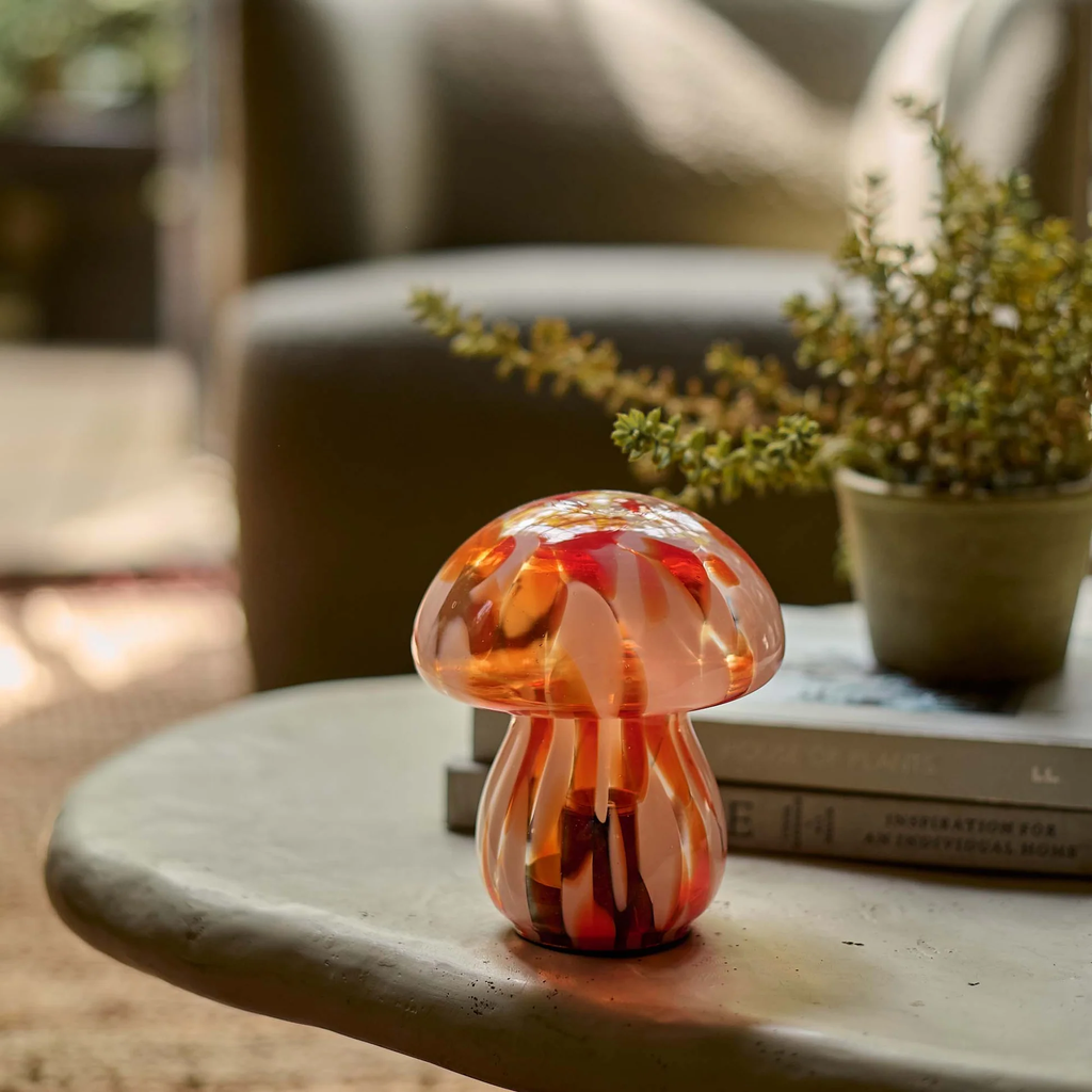 Glass mushroom ornament on a table with a blurred indoor background