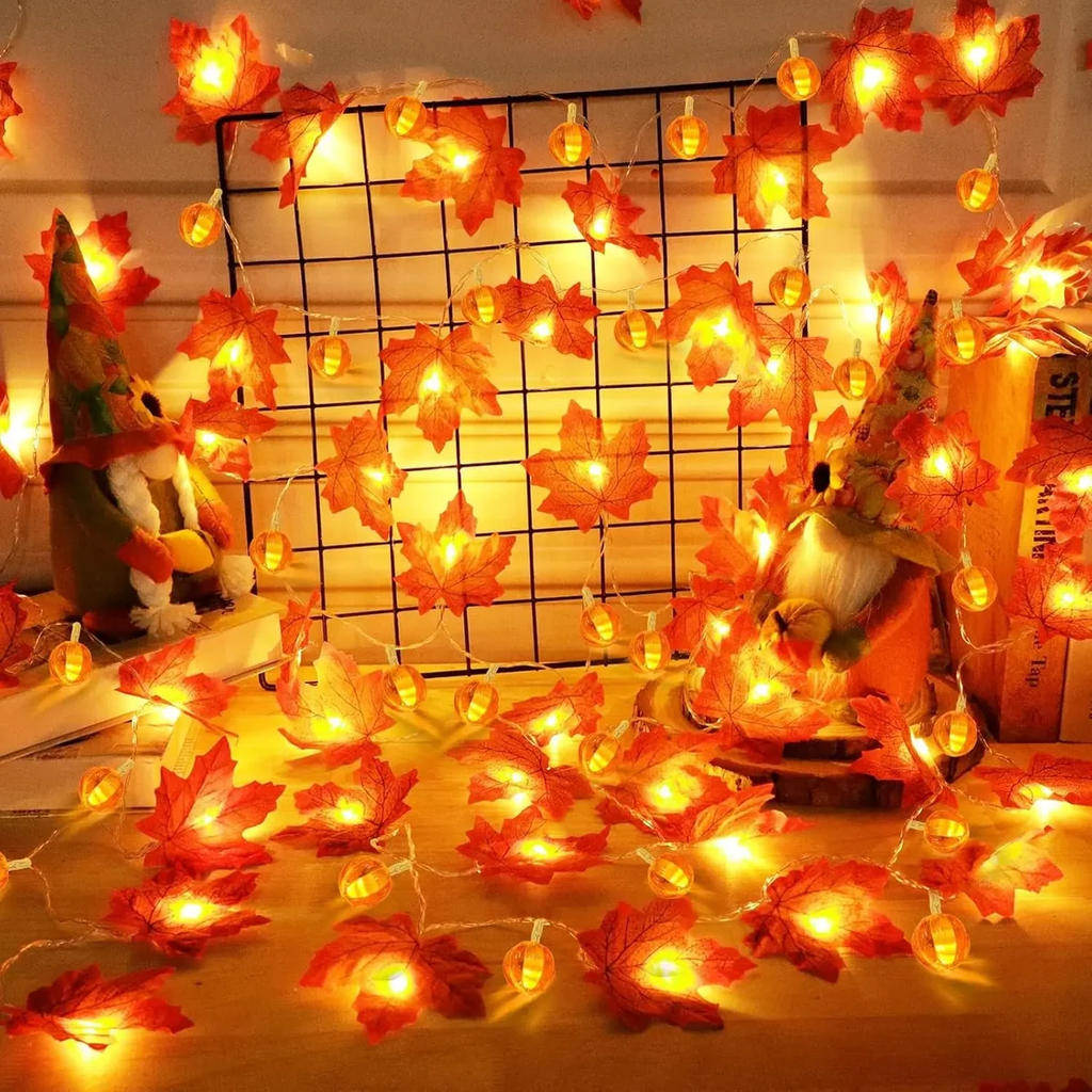 Warm white LED string lights with red and orange artificial maple leaves, decorated around a black wire grid and gnome figurines in a cozy indoor setting.