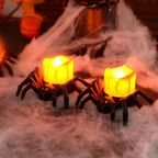 Two spider-shaped candles with glowing yellow lights on a foggy surface, likely for Halloween decor.