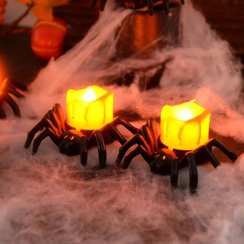 Two spider-shaped candles with glowing yellow lights on a foggy surface, likely for Halloween decor.