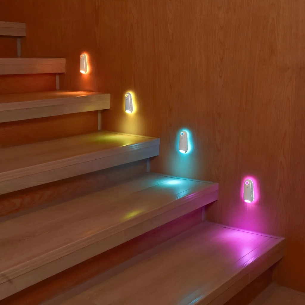 Wooden staircase with colorful night lights attached to the wall.