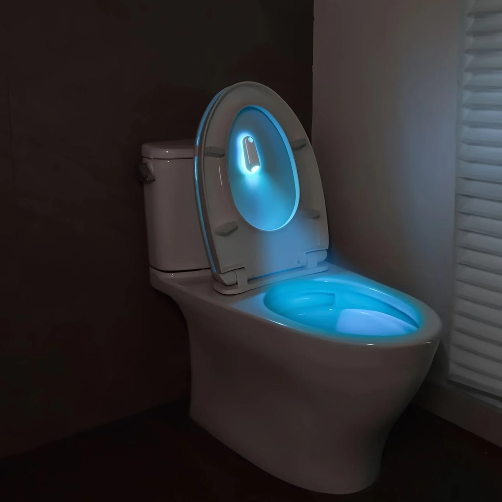 Toilet with glowing seat in a dark bathroom