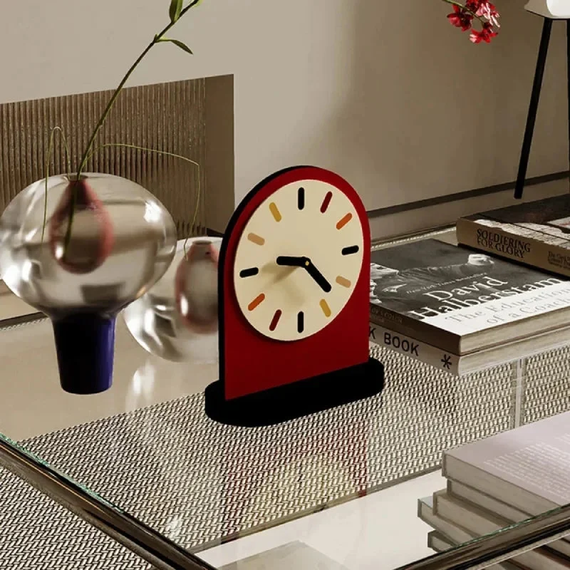 Decorative clock on a glass table with books and a vase in the background