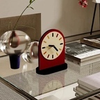 Decorative clock on a glass table with books and a vase in the background