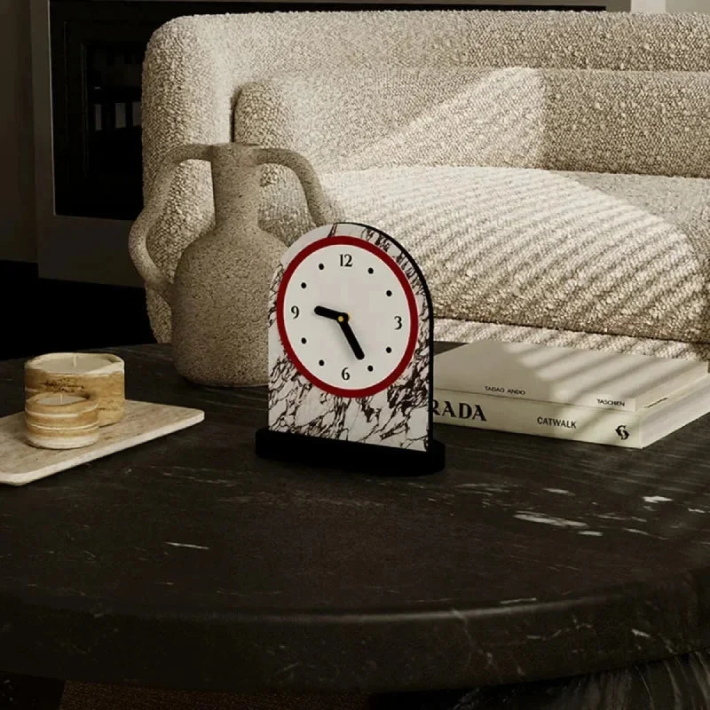 Marble-patterned clock on a table with books and a vase in the background