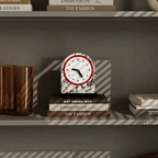 Marble clock on a shelf with books and decorative items
