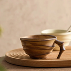Wooden cup with handle on a wooden surface
