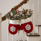 Decorative red mittens with white snowflakes filled with greenery and berries hanging on a staircase.
