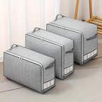 Set of gray storage bags with zippers on a light wooden floor.