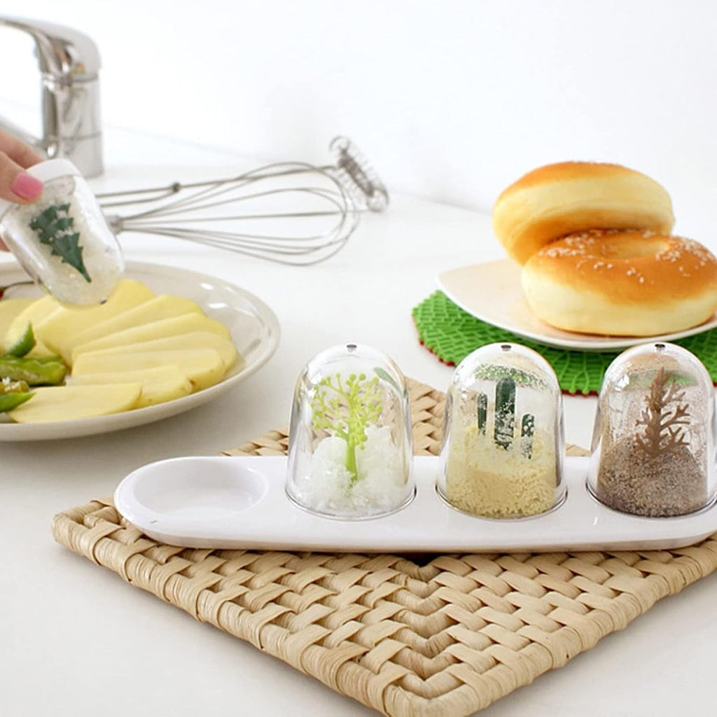 Three glass dome terrariums on a white tray, with sliced cheese, sandwiches, whisk, faucet, and woven placemat
