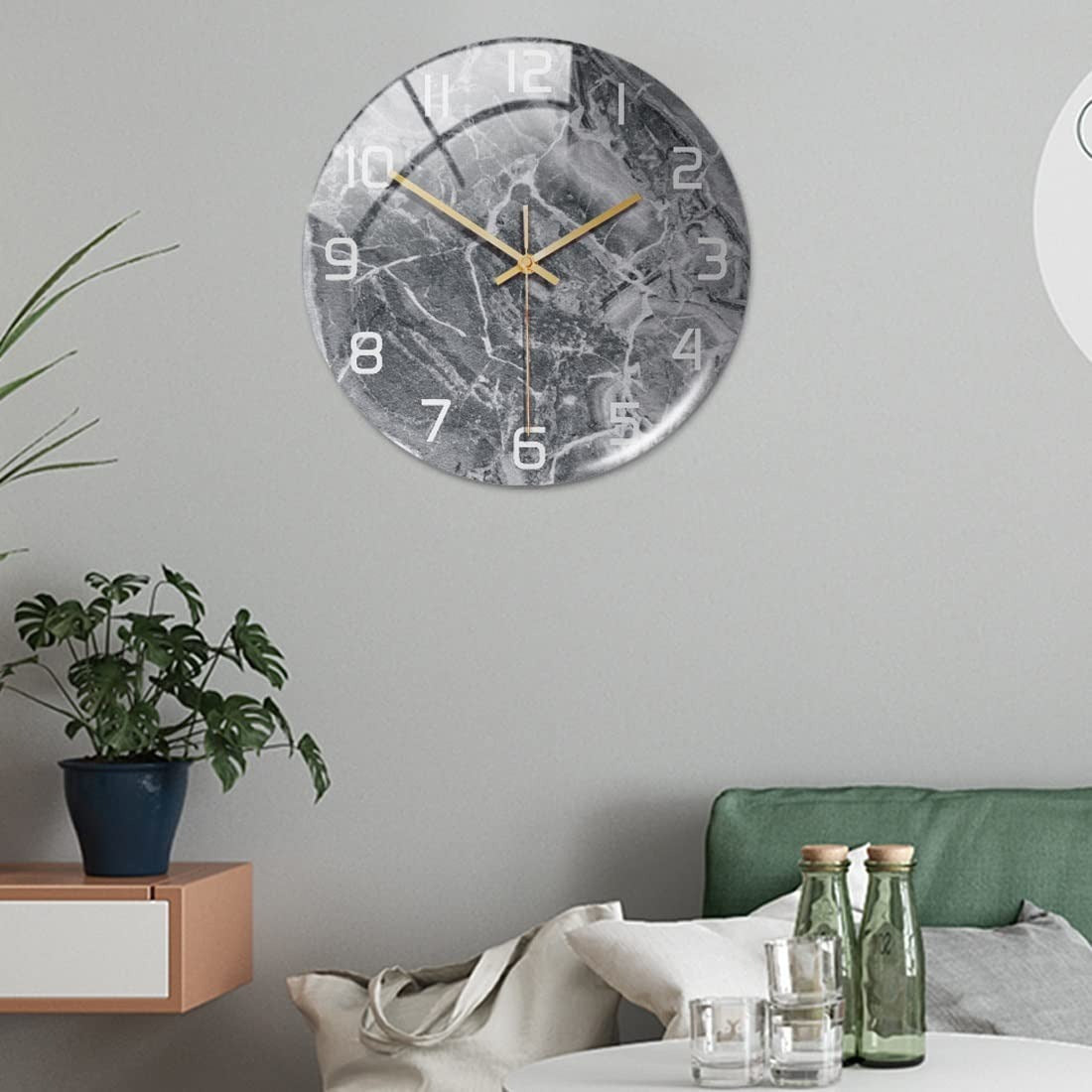 Decorative wall clock on a gray wall with a plant and furniture in the background