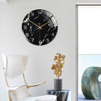 Black marble wall clock on a white wall with a modern chair and decorative items.