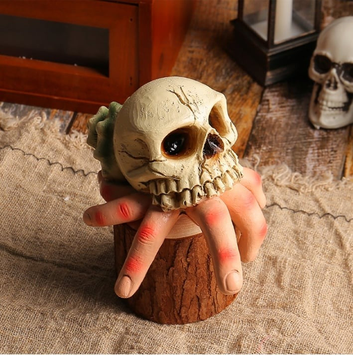 Skull-shaped object held by a hand on a rustic background