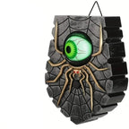 Halloween wall hanging decoration shaped like a spider with a glowing green eye, shown on a white background with three circular inset detail views labeled 'Sturdy hook,' 'Scary Ghost Eye,' and 'Solid quality.'.