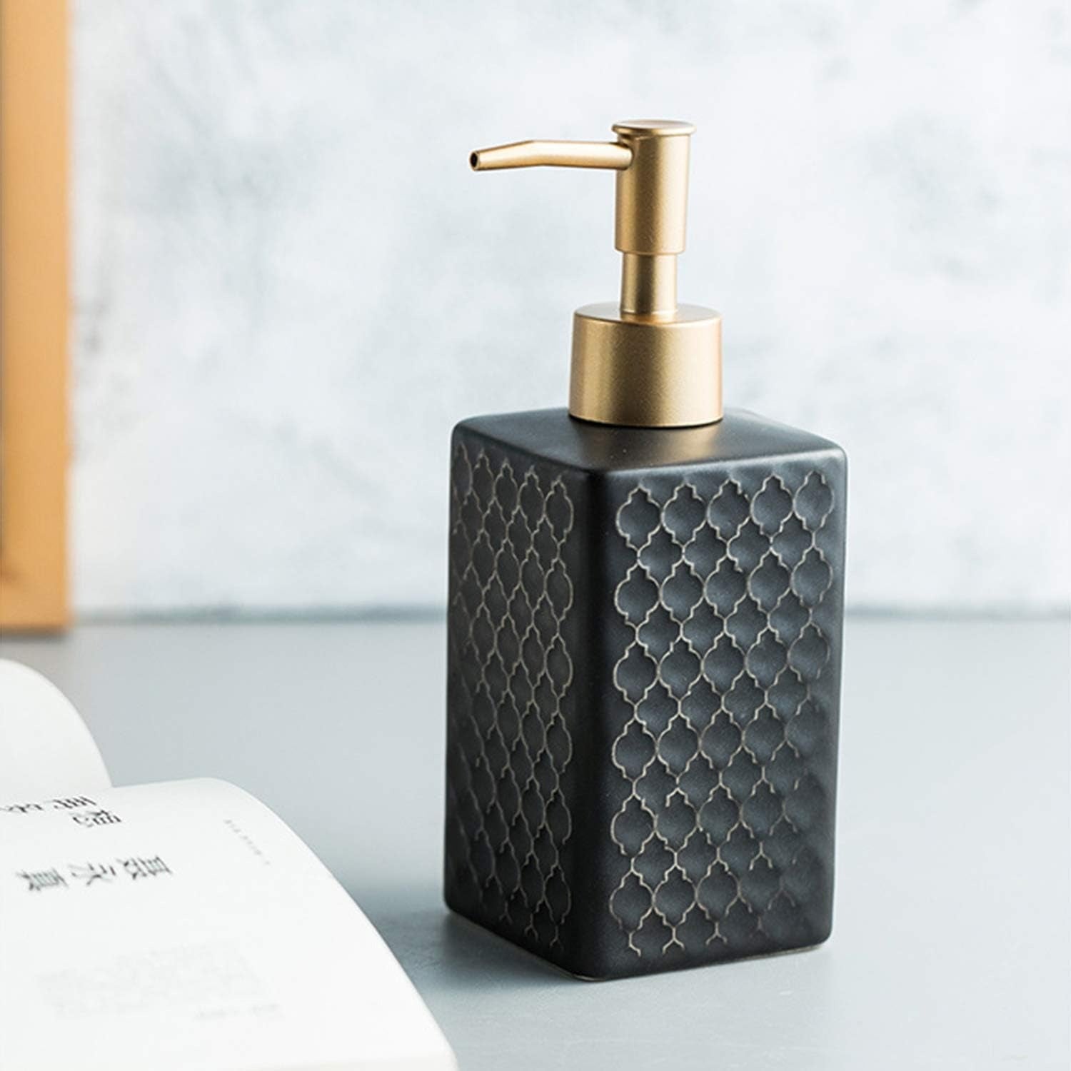 Black soap dispenser with gold pump on a light surface