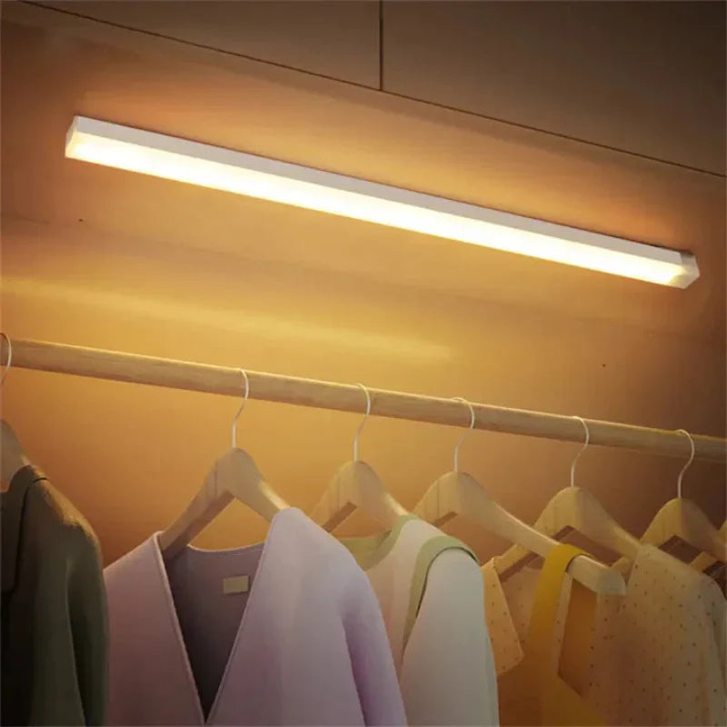 Closet light fixture above hanging clothes with a warm glow