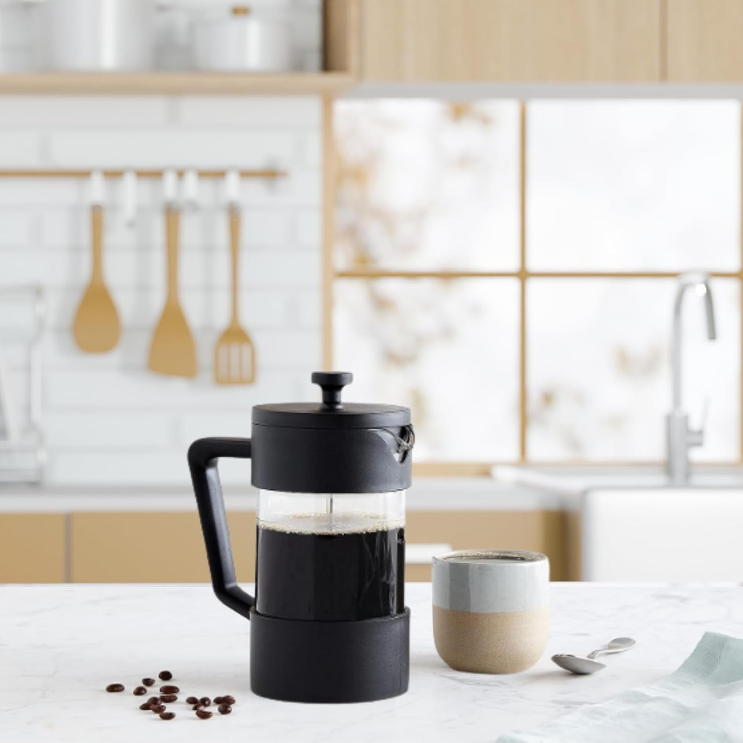 Black French press with coffee on a kitchen counter