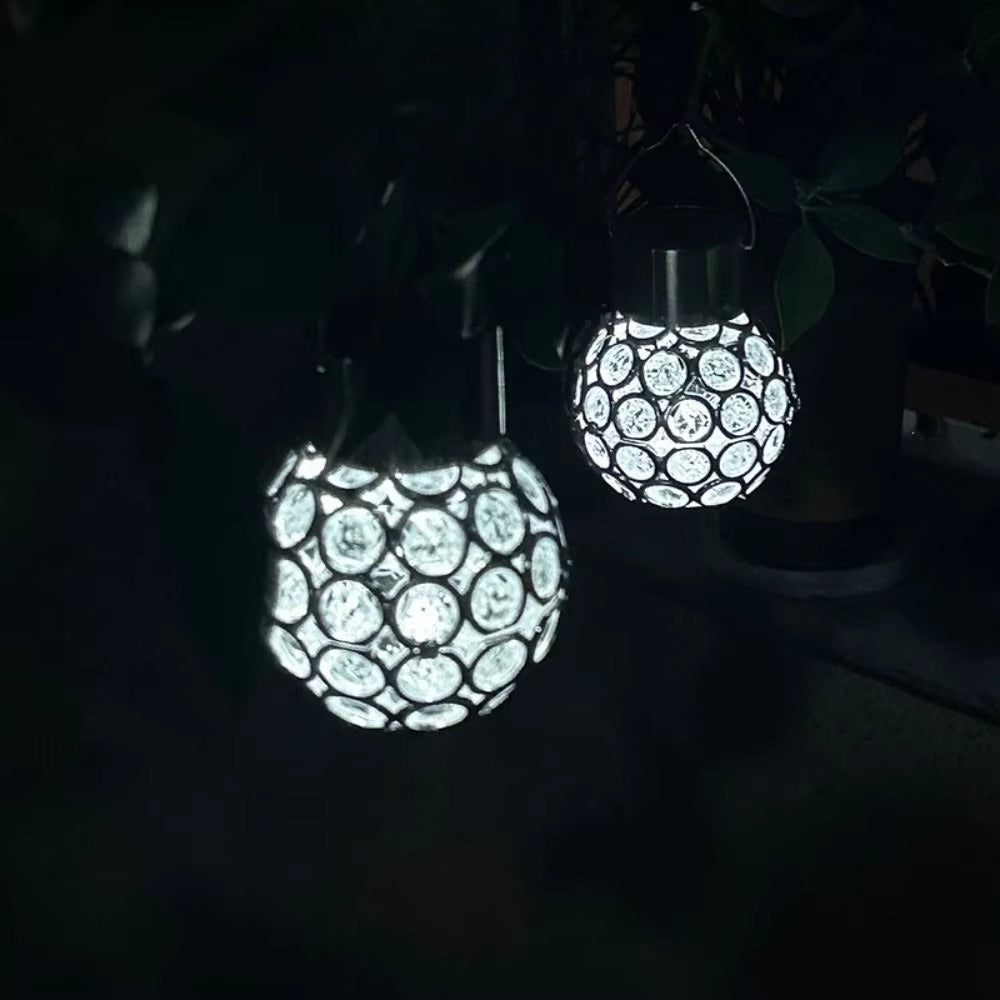 Two solar-powered hanging garden lights with a honeycomb pattern, glowing brightly in a dark outdoor setting.