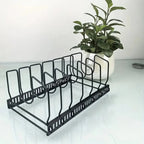 Black dish rack on a white surface with a plant in the background