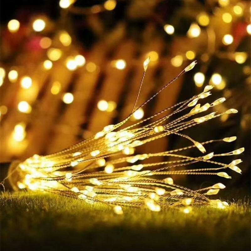 Warm white LED fairy string lights draped across green grass, with glowing bokeh lights in the background.