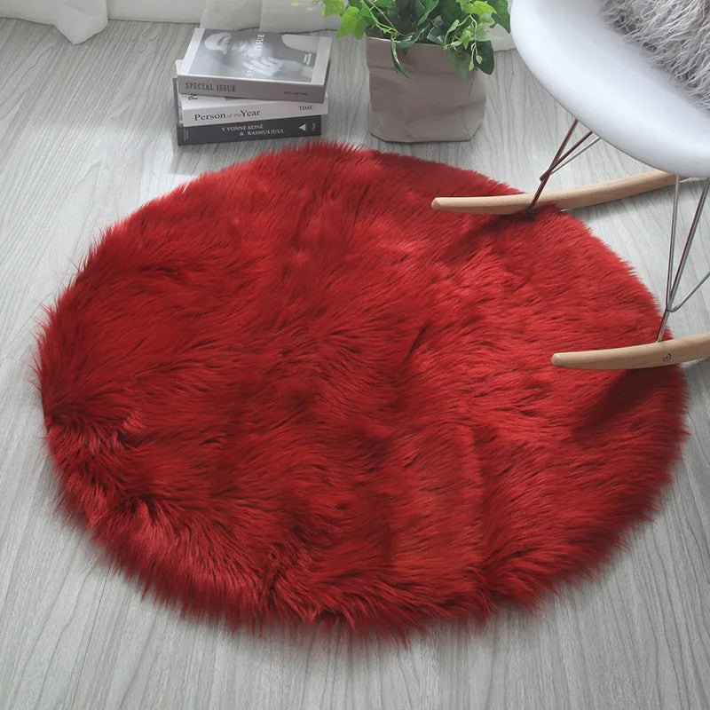 Red fluffy rug on a light wooden floor with a plant and books in the background.
