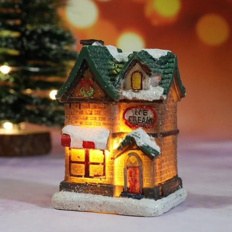 Decorative ice cream shop model with snow and lights, blurred Christmas tree in the background