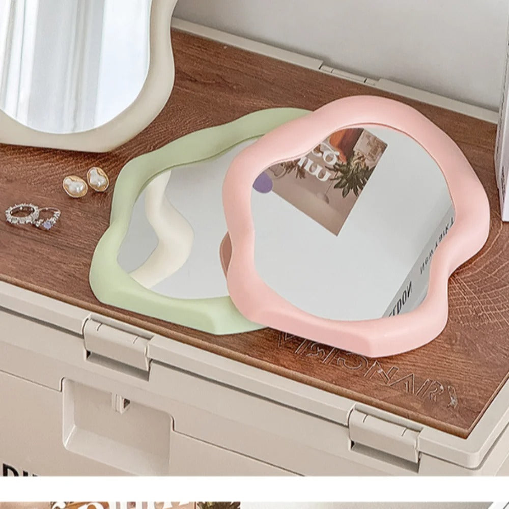 Heart-shaped mirrors in pink and green on a wooden surface with jewelry.
