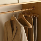 Brown coat and pants hanging on wooden hangers in a closet.