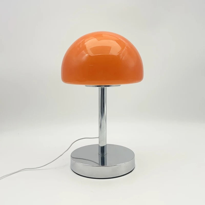 Orange table lamp with a chrome base on a white background