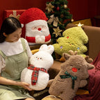 Woman sitting with plush toys in a cozy room with a Christmas tree.