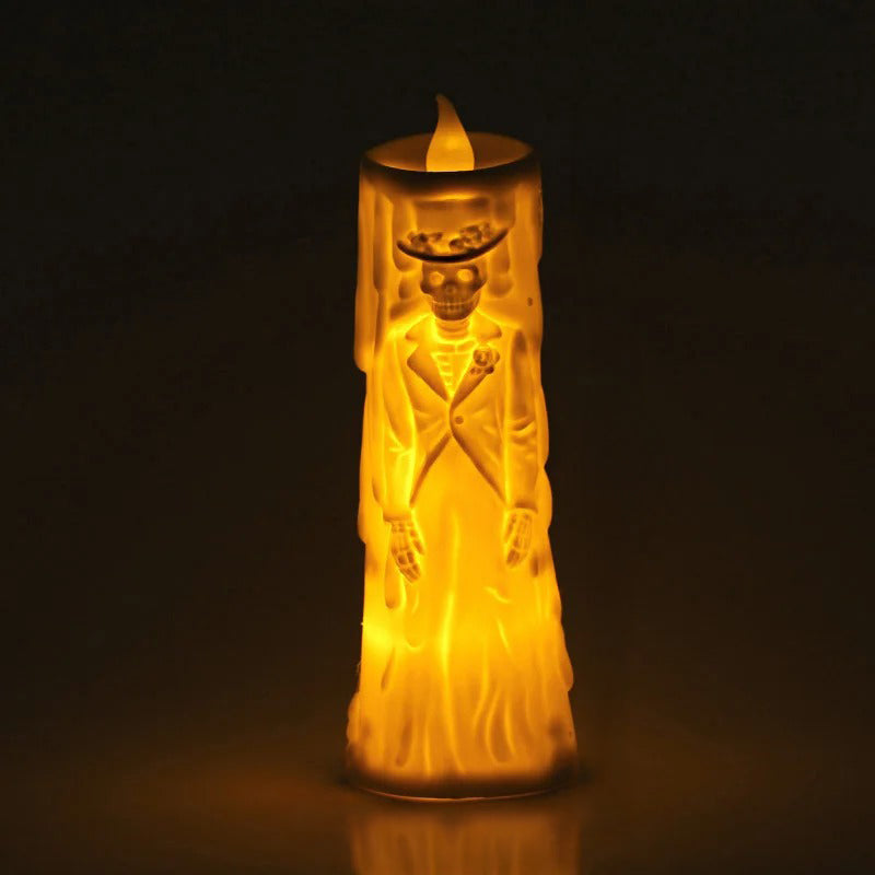 A glowing LED wax candle shaped like a skeleton bride in a wedding dress and hat, emitting a warm yellow light against a dark background.