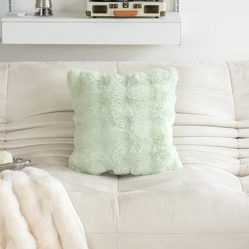 Light green textured pillow on a white sofa with a neutral background