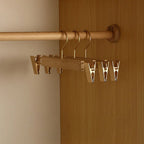 A wooden closet rod organizer with metal hangers and clips mounted on a wooden wardrobe door and rod, shown in a real interior setting.