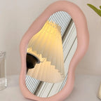 Pink mirror reflecting a lamp on a white surface with a neutral background