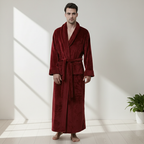 Man wearing a red robe standing in a bright room with a plant in the corner.
