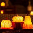 Three illuminated pumpkin-shaped lights on a dark background with blurred lights in the background