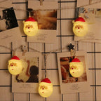 String lights with Santa Claus design hanging on a wall with photos and notes.