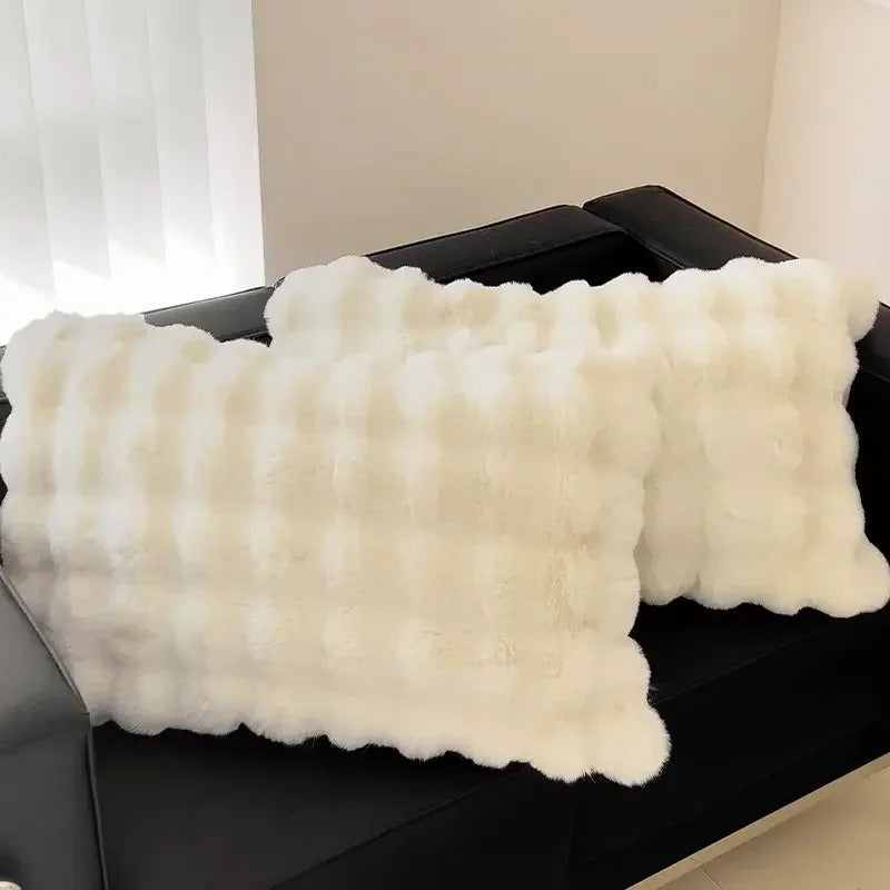Two fluffy white pillows on a black surface with a neutral background