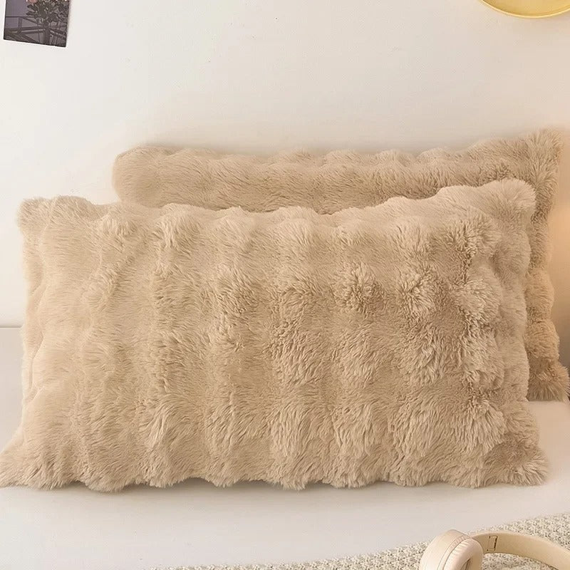 Beige fluffy pillows on a white surface with a neutral background