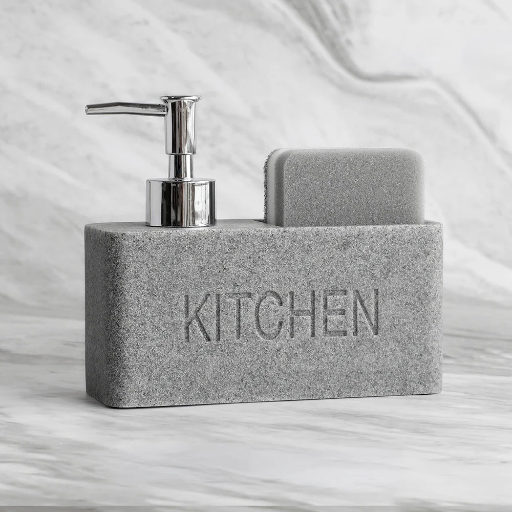 Gray soap dispenser with pump and sponge on a marble surface